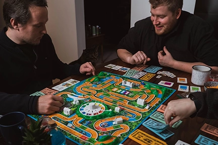 Vrienden verzameld rond een tafel spelen samen een kleurrijk strategie bordspel.
